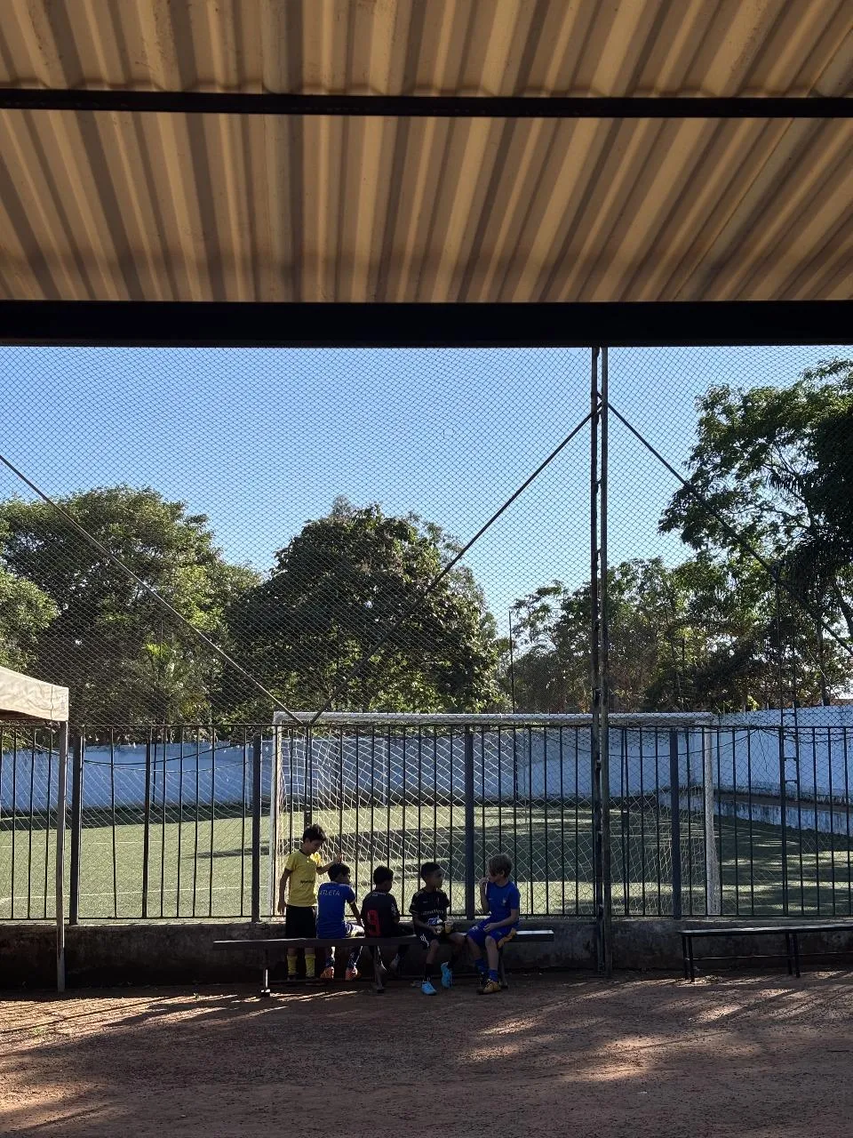 Crianças reunidas no banco ao lado do campo