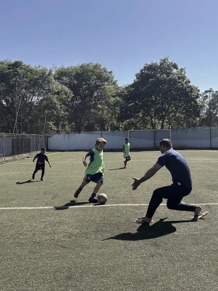 Adulto e criança disputando a bola durante uma atividade do projeto