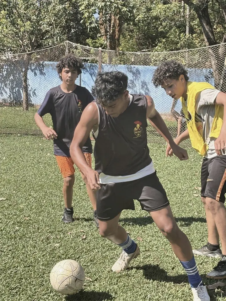 Jovens disputando a bola em campo aberto