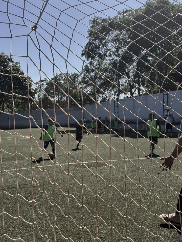 Partida vista de trás da rede do gol, no campo do Projeto Roma