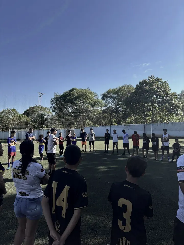 Participantes reunidos na lateral do campo acompanhando a partida